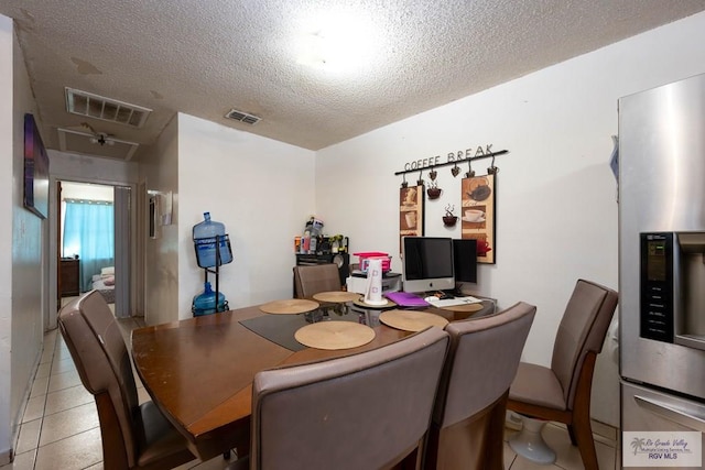 dining space featuring light tile patterned floors, visible vents, and a textured ceiling