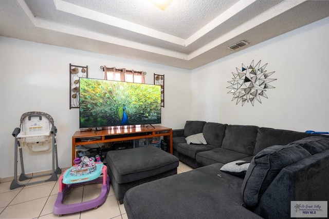 tiled living room with visible vents, a textured ceiling, and a tray ceiling