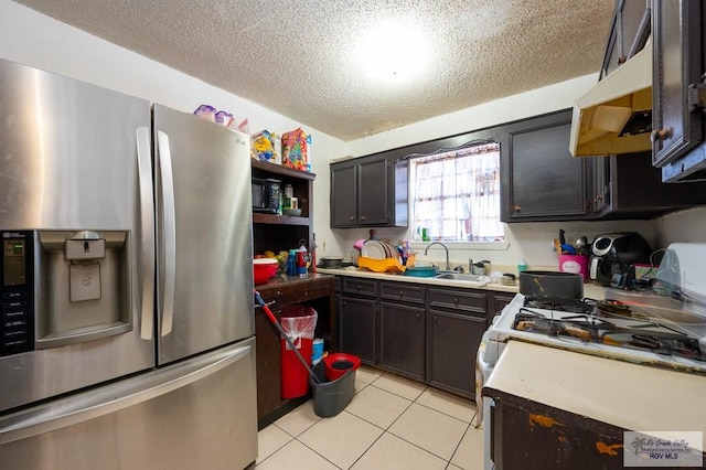 kitchen with white gas stove, stainless steel refrigerator with ice dispenser, a textured ceiling, light countertops, and light tile patterned floors