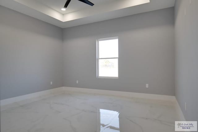 empty room featuring baseboards, ceiling fan, a tray ceiling, recessed lighting, and marble finish floor