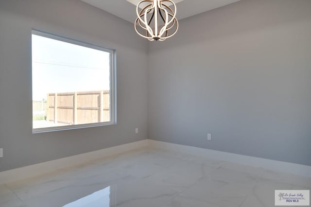 unfurnished room featuring baseboards, marble finish floor, and a chandelier