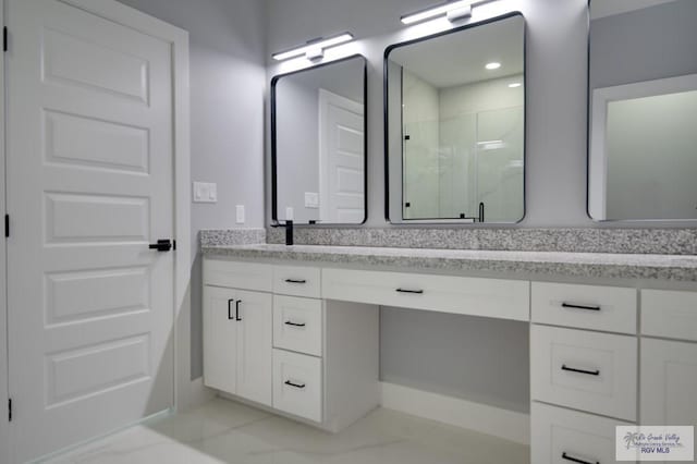 bathroom featuring double vanity, marble finish floor, and a stall shower