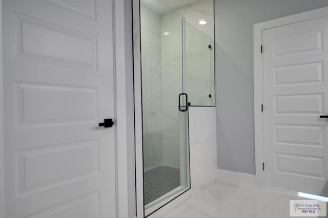 bathroom featuring a marble finish shower, marble finish floor, and baseboards