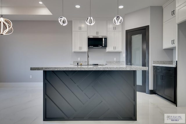 kitchen featuring white cabinetry, stainless steel microwave, recessed lighting, and marble finish floor