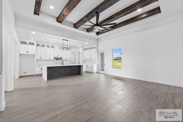 unfurnished living room with ceiling fan and beam ceiling