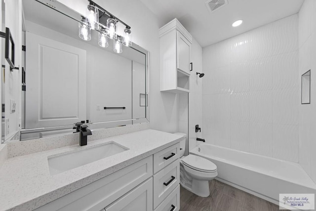 full bathroom with toilet, vanity, hardwood / wood-style floors, and washtub / shower combination