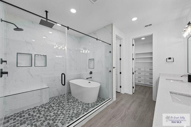 bathroom featuring independent shower and bath, sink, and wood-type flooring