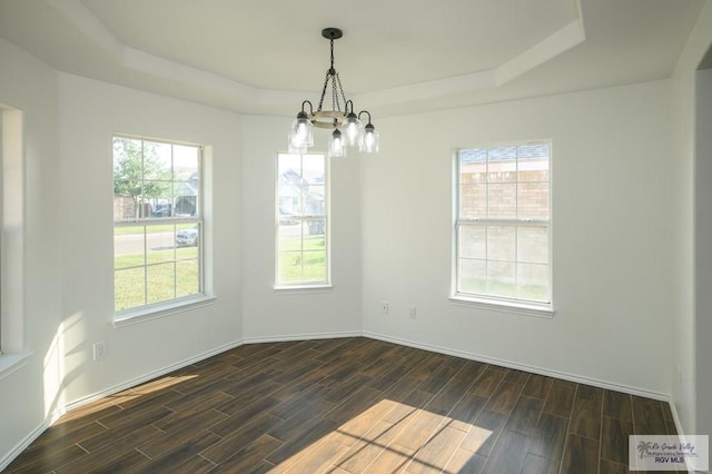 spare room featuring a wealth of natural light, dark wood-type flooring, and an inviting chandelier