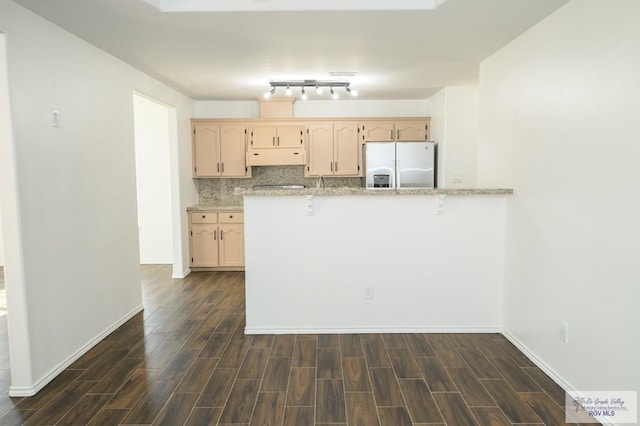 kitchen featuring light stone countertops, dark hardwood / wood-style floors, stainless steel refrigerator with ice dispenser, backsplash, and light brown cabinetry