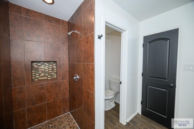 bathroom with tiled shower and toilet