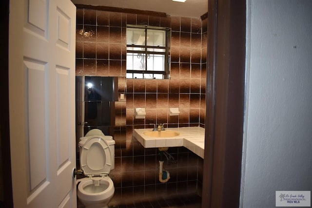 bathroom featuring tile walls, backsplash, sink, and toilet