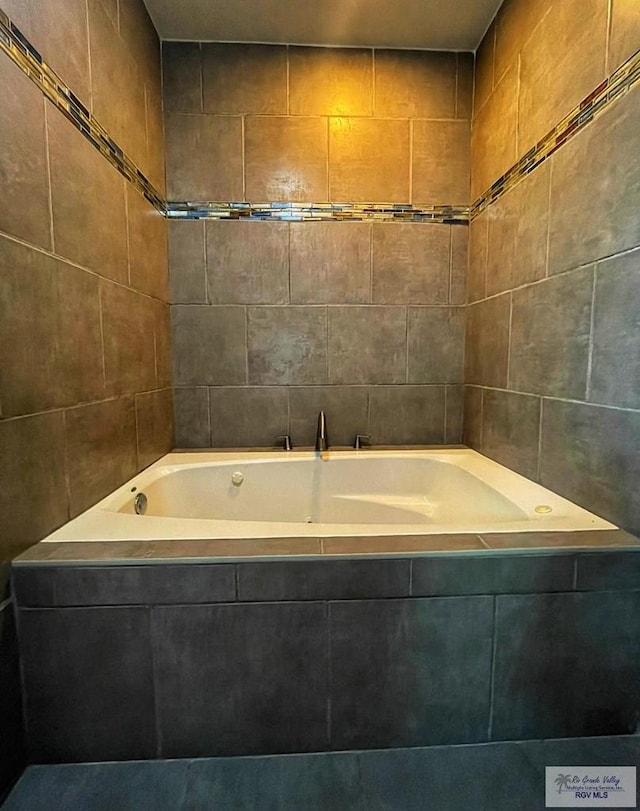 bathroom with tiled tub and tile walls