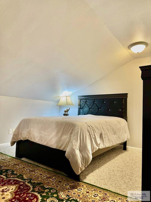 bedroom with carpet, a textured ceiling, and vaulted ceiling