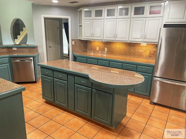 kitchen featuring white cabinetry, stainless steel appliances, tasteful backsplash, light tile patterned floors, and green cabinetry