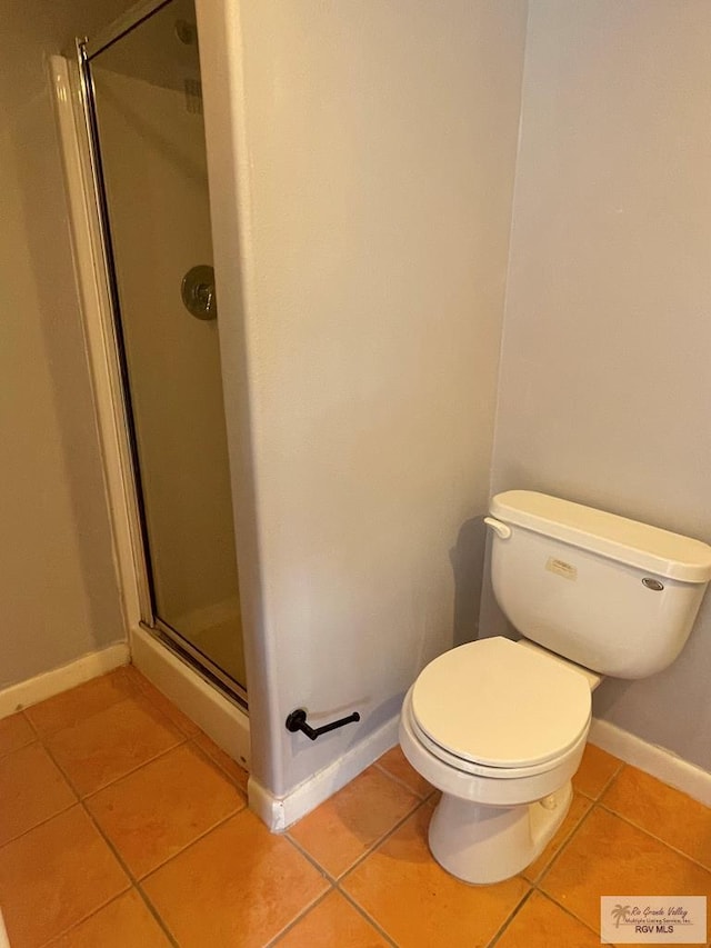 bathroom featuring tile patterned floors, toilet, and a shower with shower door