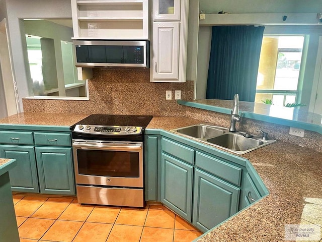 kitchen with green cabinets, sink, light tile patterned floors, and stainless steel appliances