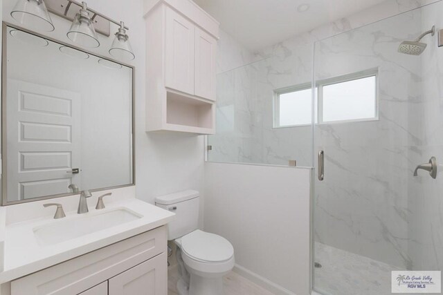 bathroom featuring vanity, toilet, and a shower with shower door