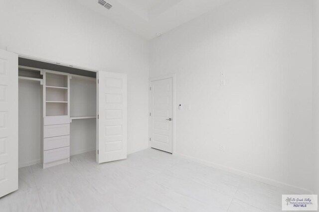 unfurnished bedroom featuring a towering ceiling and a closet