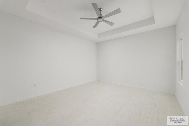 empty room with a raised ceiling and ceiling fan