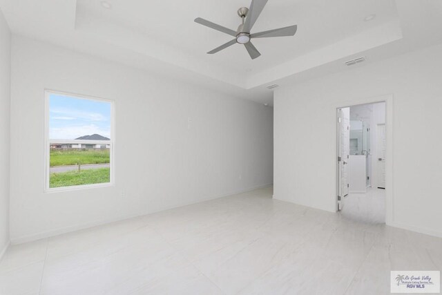 spare room featuring a tray ceiling and ceiling fan