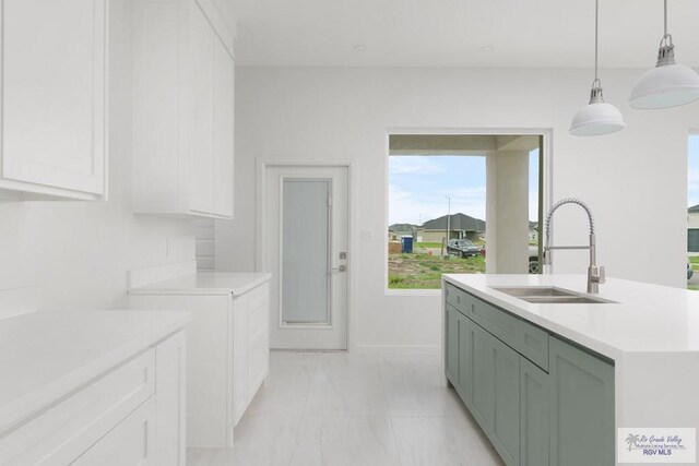 kitchen with white cabinets, a kitchen island with sink, hanging light fixtures, and sink