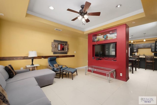 living room featuring a tray ceiling, ceiling fan, and ornamental molding