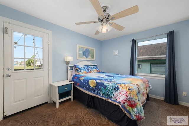 bedroom with multiple windows, dark colored carpet, and ceiling fan