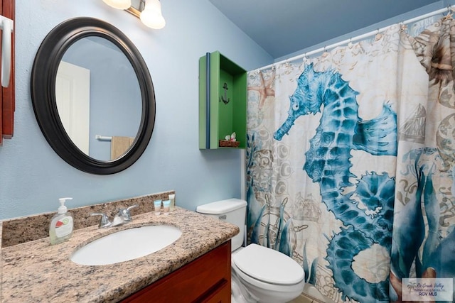 bathroom with walk in shower, vanity, and toilet