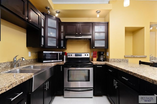 kitchen featuring dark brown cabinets, light stone counters, light tile patterned floors, and appliances with stainless steel finishes