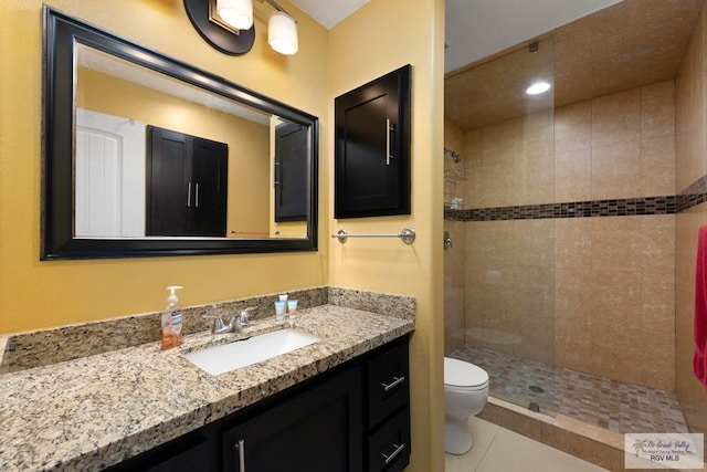 bathroom with tile patterned floors, vanity, toilet, and a tile shower