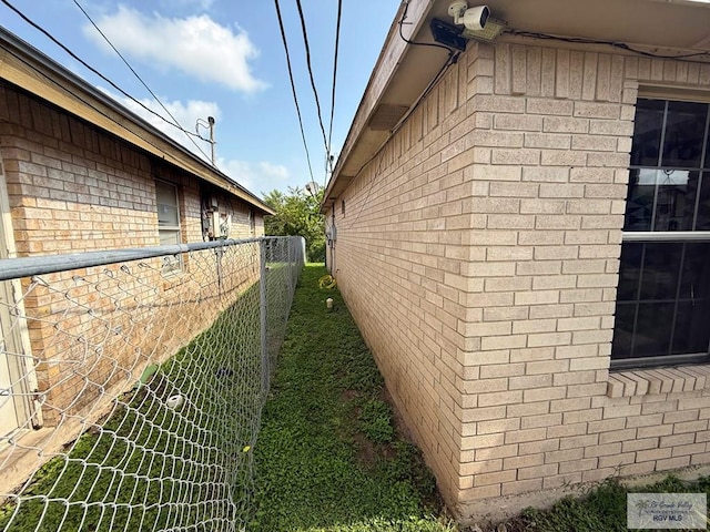 view of home's exterior with fence and brick siding