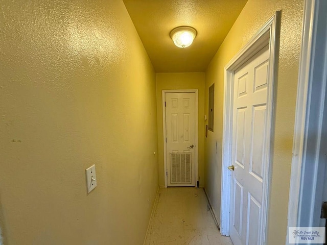corridor featuring baseboards, electric panel, and visible vents