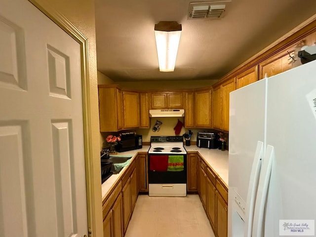 kitchen featuring brown cabinetry, freestanding refrigerator, light countertops, under cabinet range hood, and electric stove