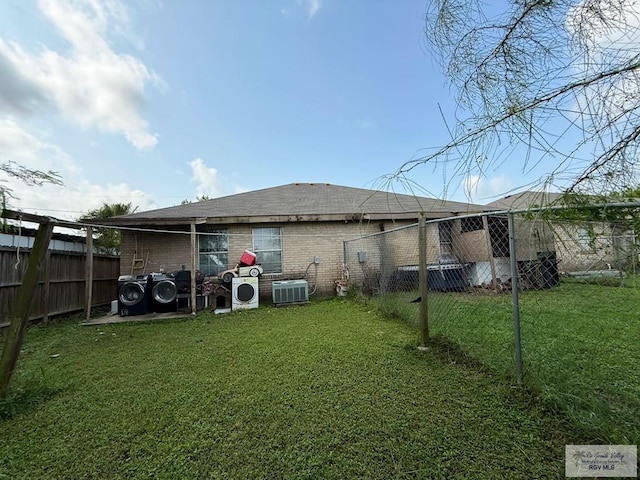 rear view of property featuring fence, cooling unit, brick siding, ac unit, and a yard