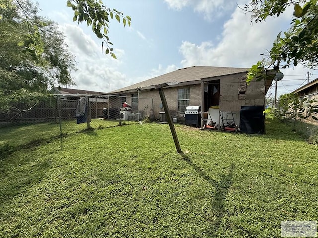 rear view of property with a lawn, brick siding, central AC, and fence