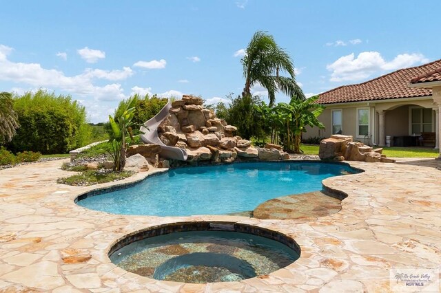 view of pool featuring a patio, an in ground hot tub, and a water slide