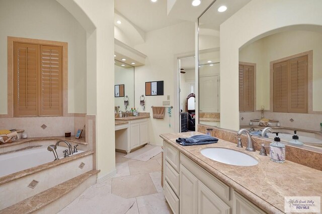 bathroom with vanity and a relaxing tiled tub