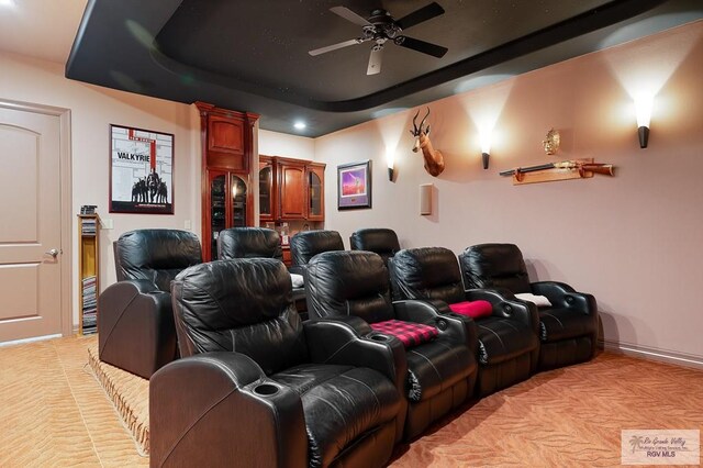 cinema room featuring ceiling fan and a tray ceiling