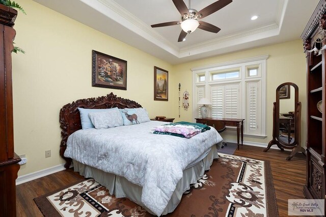 bedroom with dark hardwood / wood-style flooring, a tray ceiling, ceiling fan, and crown molding