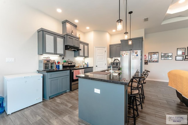 kitchen featuring pendant lighting, white refrigerator, light hardwood / wood-style flooring, fridge, and stainless steel electric range