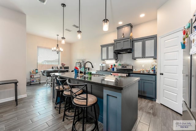 kitchen with pendant lighting, an island with sink, a notable chandelier, and stainless steel electric range