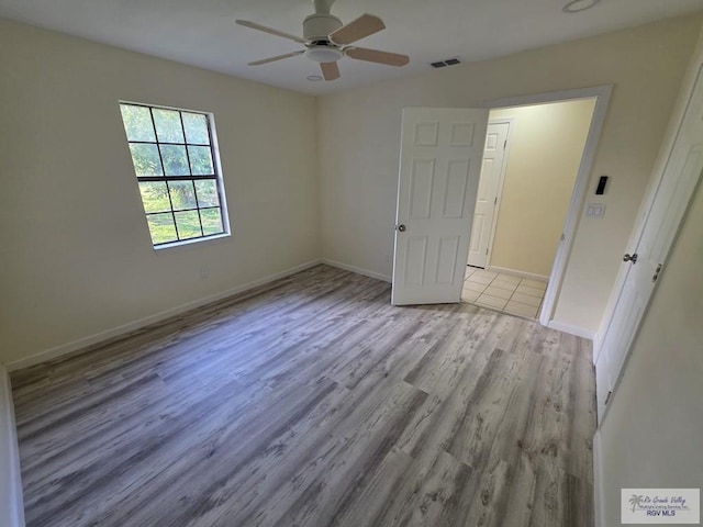 spare room with wood finished floors, baseboards, a ceiling fan, and visible vents