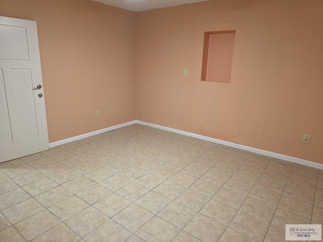 spare room featuring light tile patterned floors and baseboards