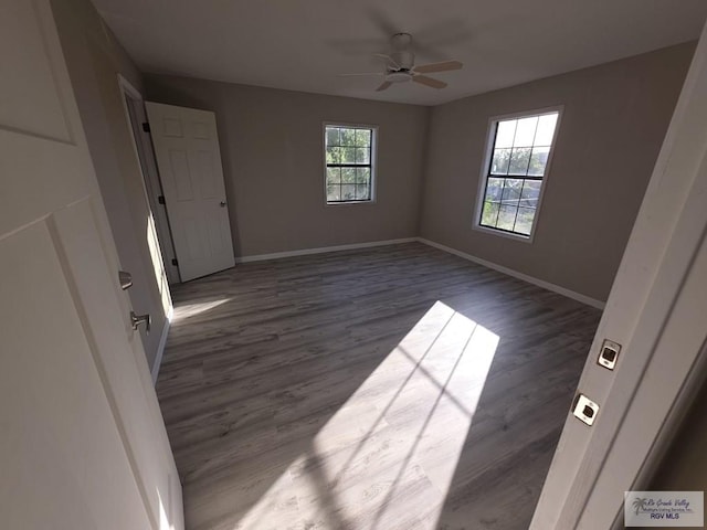 unfurnished bedroom with ceiling fan, baseboards, and dark wood finished floors