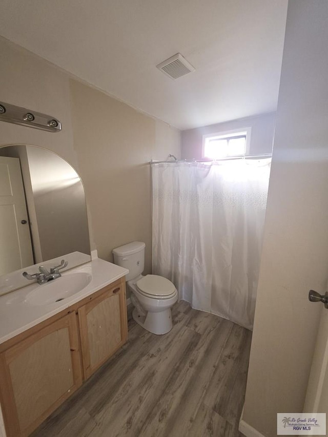 full bath featuring vanity, visible vents, toilet, wood finished floors, and a shower with shower curtain