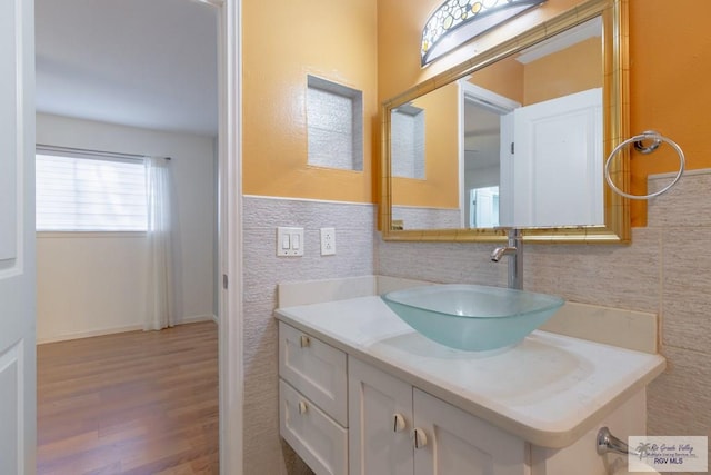 bathroom featuring vanity, wood-type flooring, and tile walls