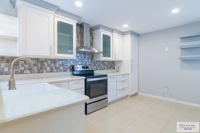 kitchen featuring backsplash, white cabinets, wall chimney range hood, sink, and electric stove