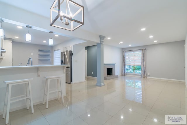 kitchen with pendant lighting, white cabinets, stainless steel fridge, light tile patterned floors, and a breakfast bar area