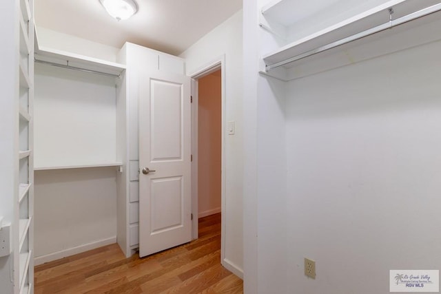 walk in closet with light hardwood / wood-style floors