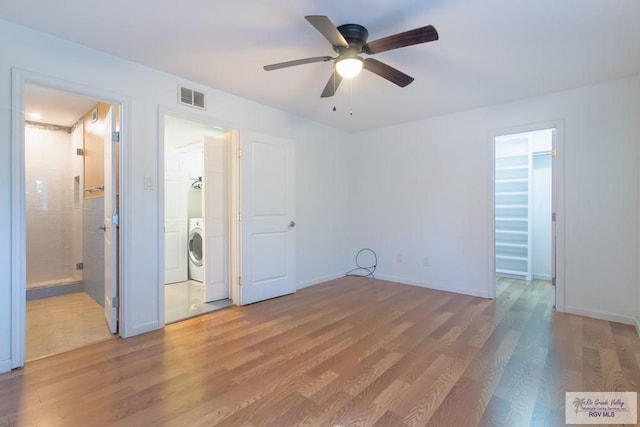 unfurnished bedroom with ensuite bath, ceiling fan, separate washer and dryer, wood-type flooring, and a walk in closet